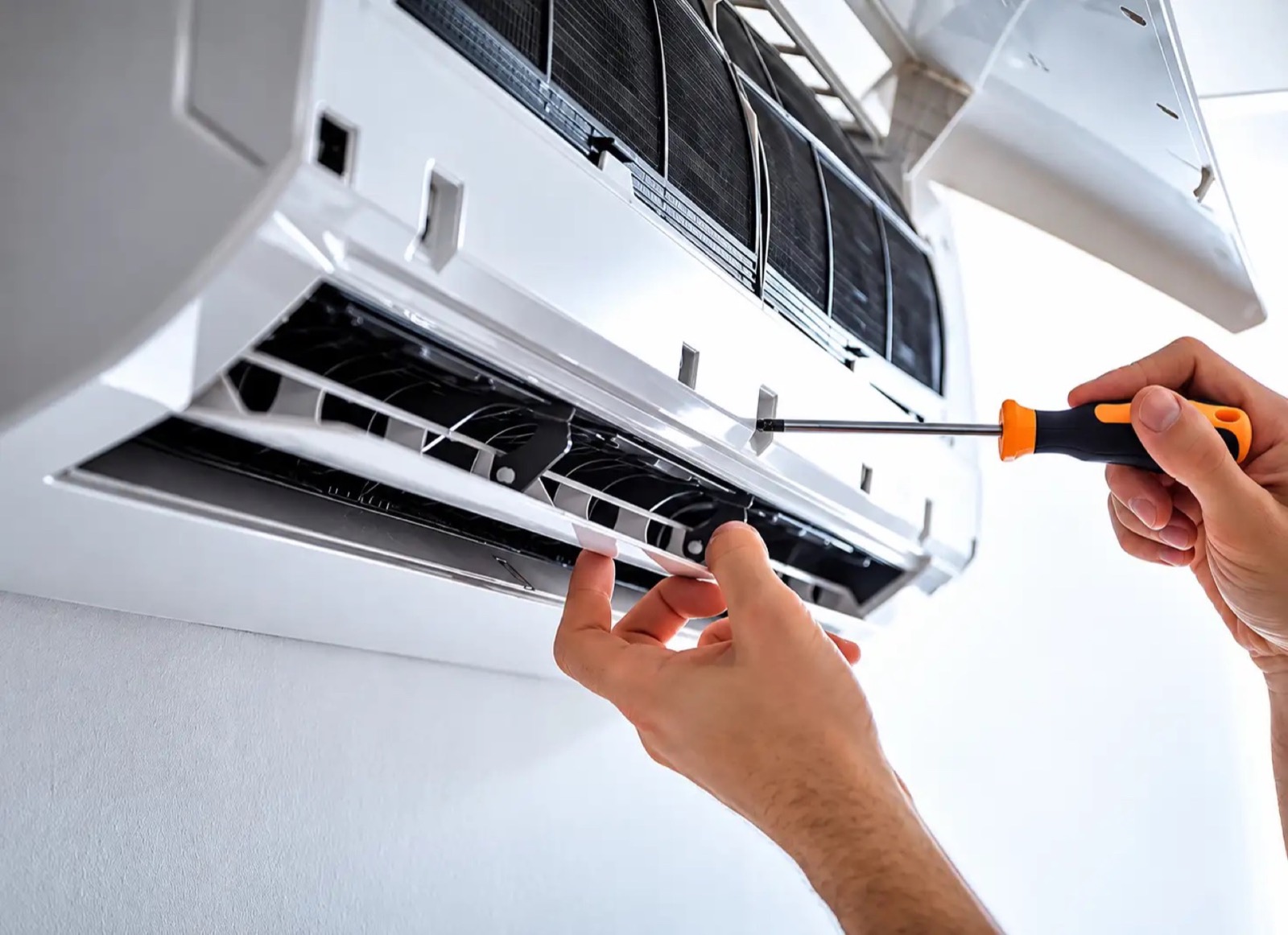 Hands using a screwdriver on the open front panel of a wall-mounted indoor unit